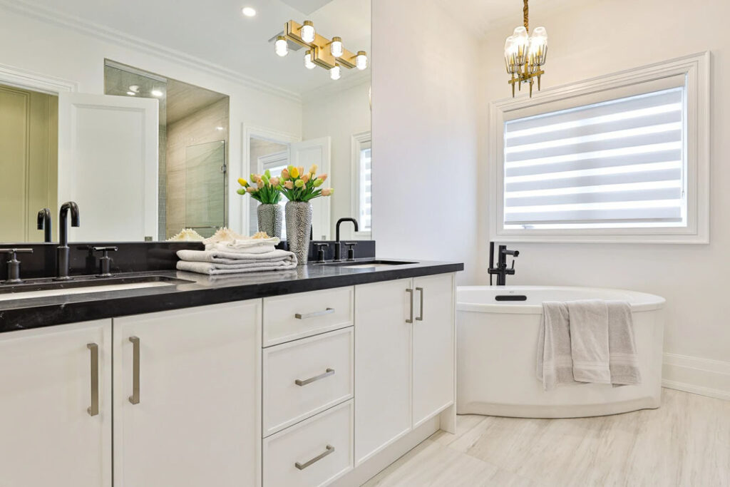 white bathroom with standing vanity and black countertop and bathtub