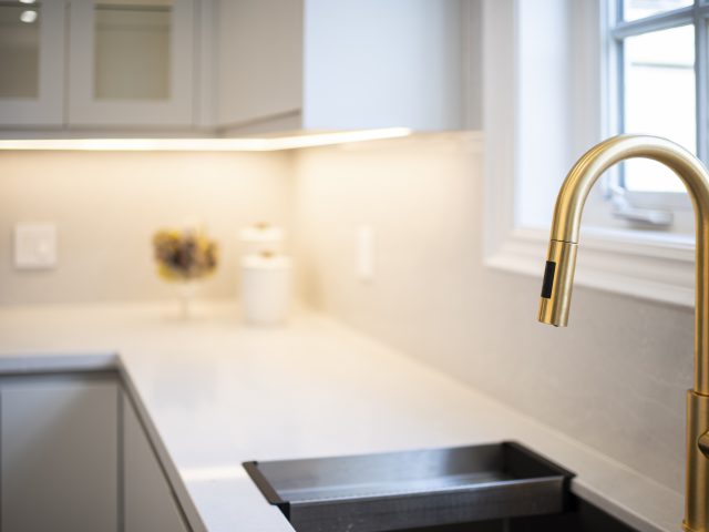 white countertop and sink with golden faucets